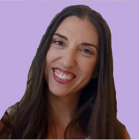 A woman with long brown hair smiling and winking at the camera against a light purple background.
